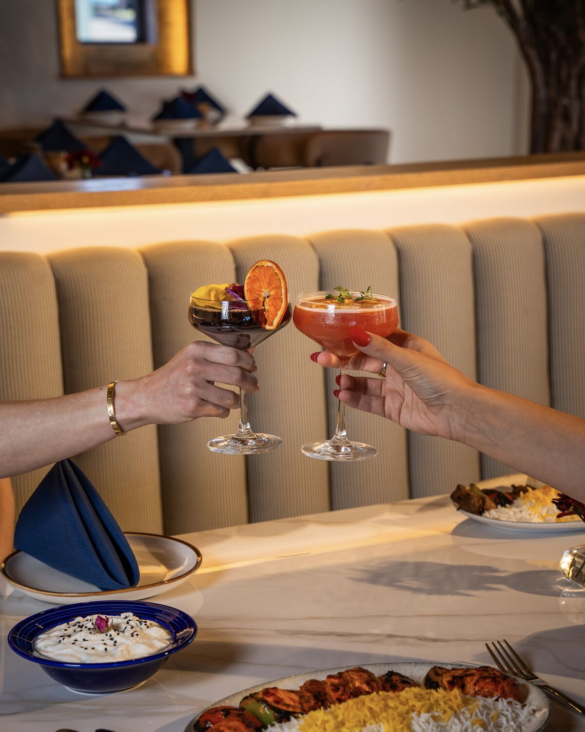 Guests toasting cocktails over a table of Persian dishes in Manhattan Beach
