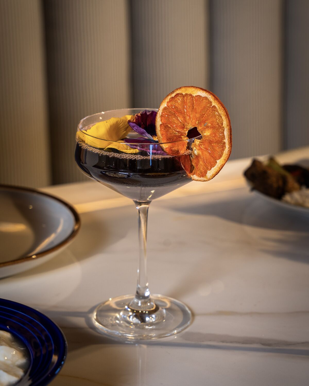 Signature cocktail garnished with dried orange and rose petals in Manhattan Beach